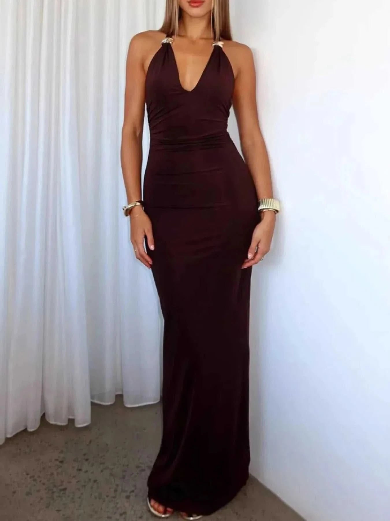 Woman wearing a black slit back halter neck maxi dress with ruched and tied details